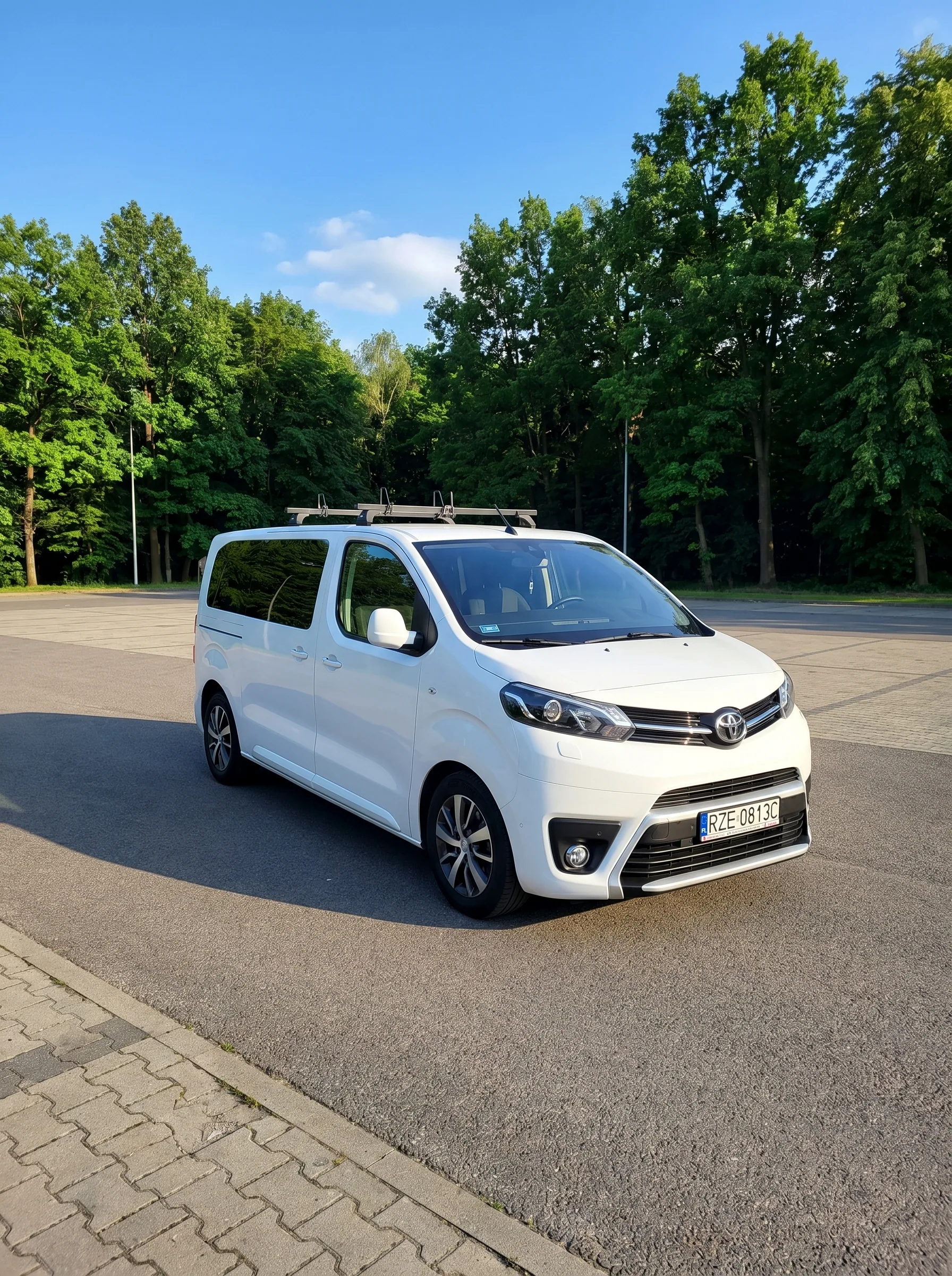 Toyota Proace Verso 2021 L2 — przód auta, tablica RZE 0813C, parking z drzewami w tle